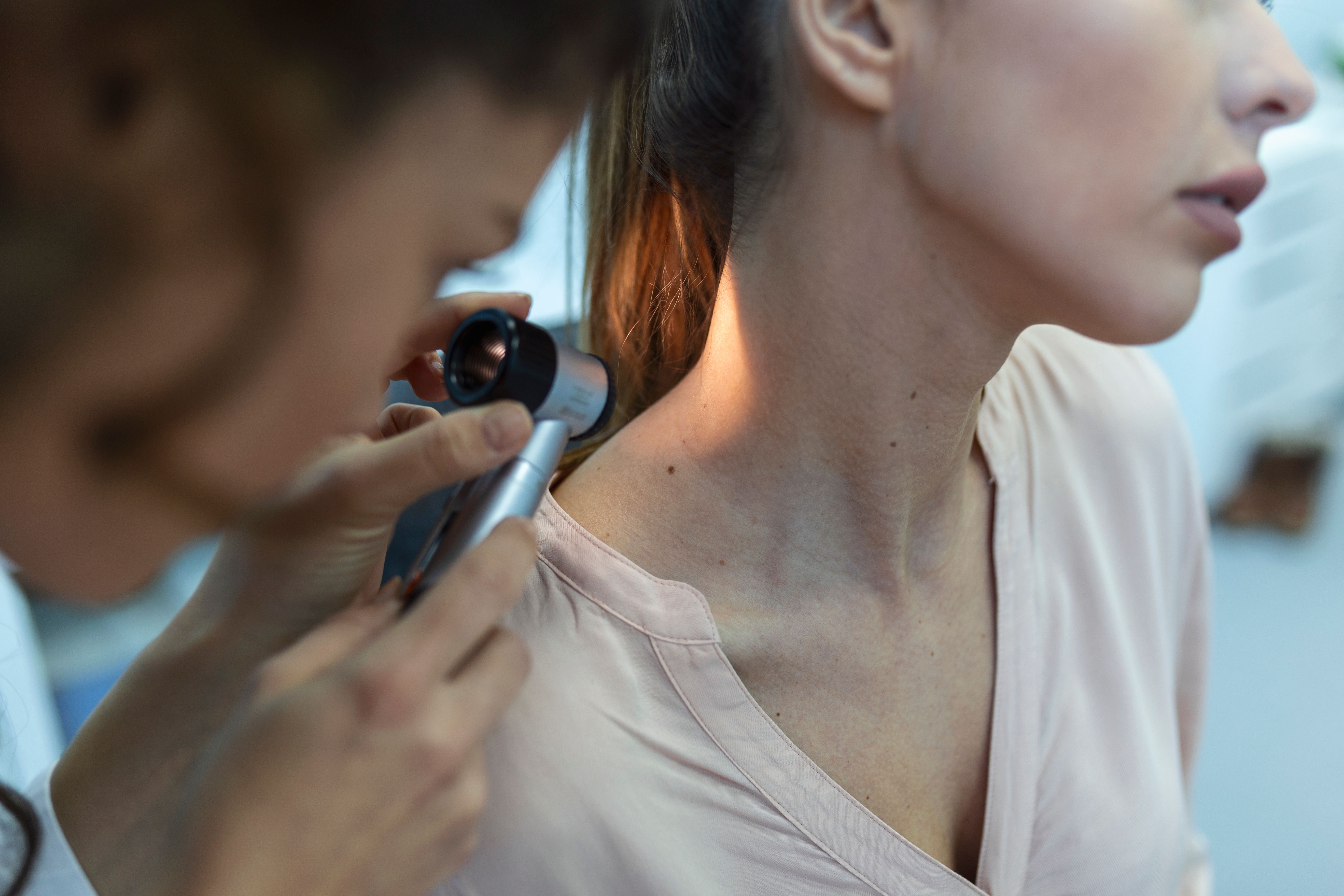 dermatologist latex gloves holding dermatoscope while examining attractive patient with skin disease female dermatologist examining patient with dermascope looking signs skin cancer