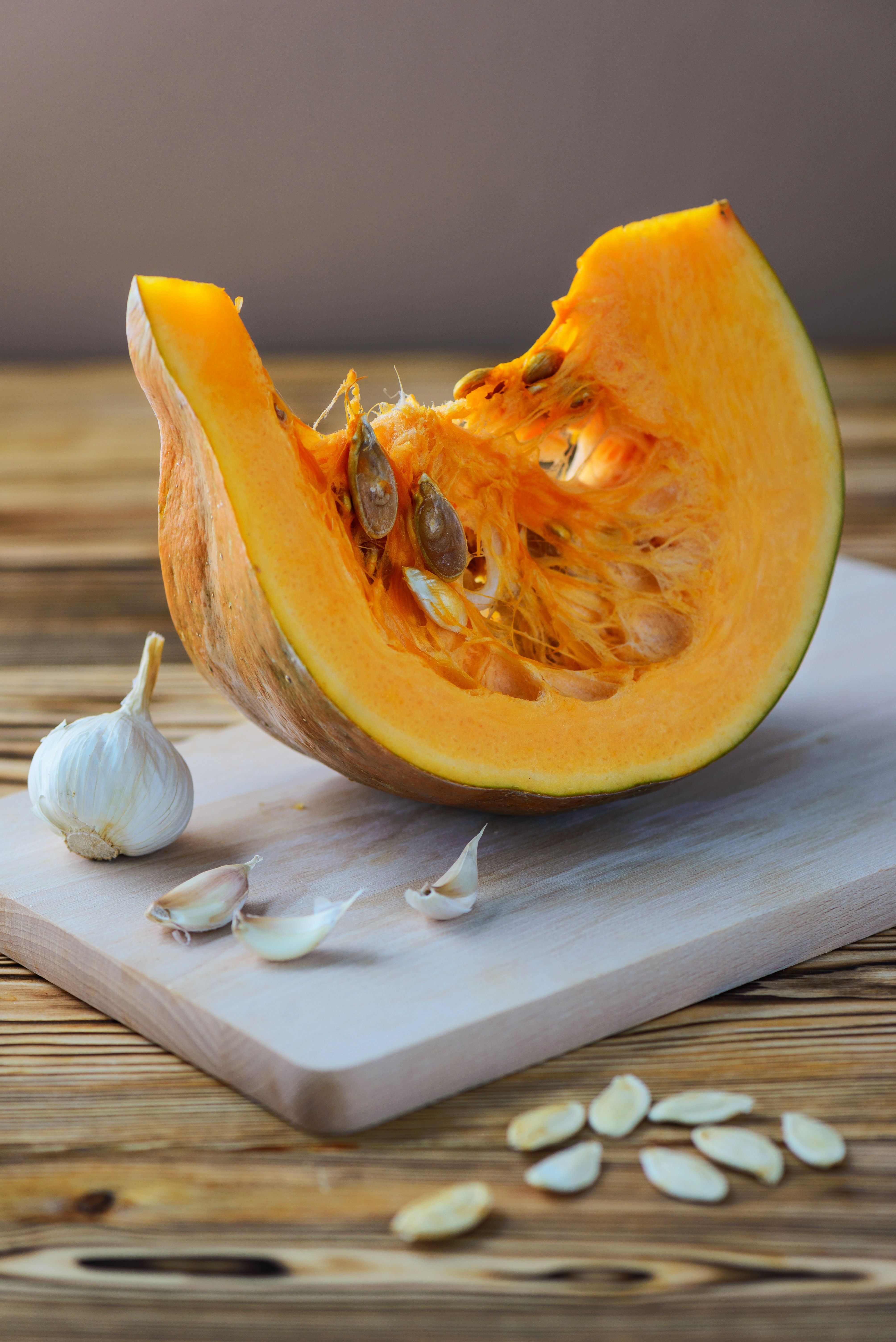 slice pumpkin with garlic seeds wooden board