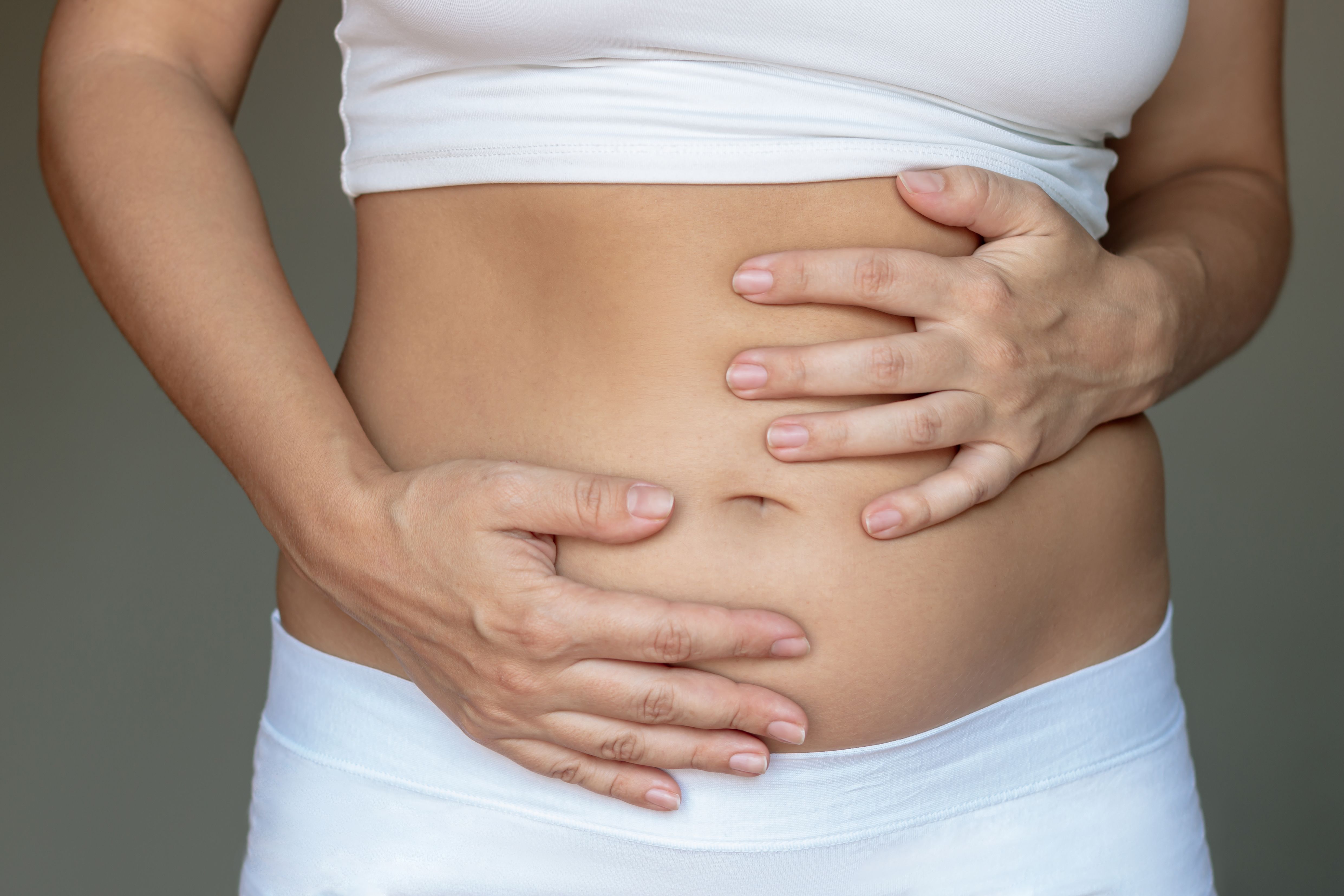 stomach ache bloating flatulence abdominal distension colic woman holding her stomach with hand